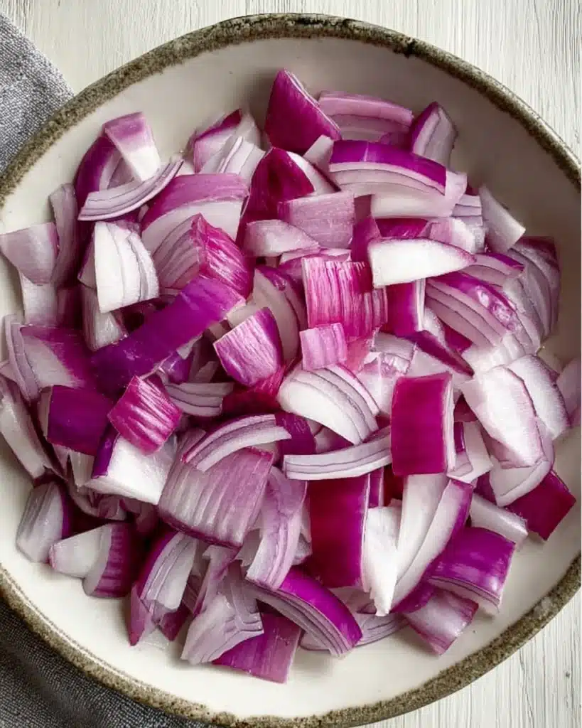 Fresh chopped red onions in a bowl for sheet pan beef kebabs