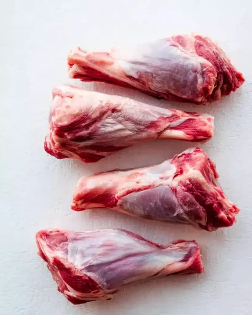 Raw lamb shanks on a white surface ready for slow cooking