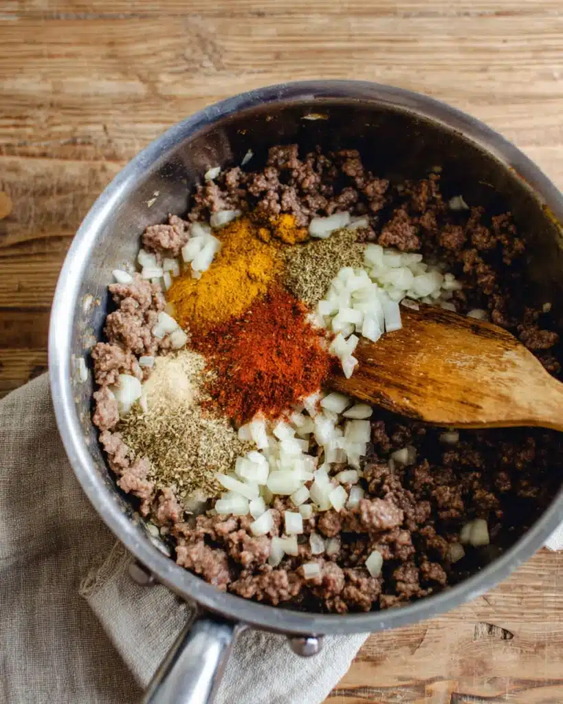 Slow Cooker Chili Recipe 3 Adding spices and garlic to ground beef for slow cooker chili