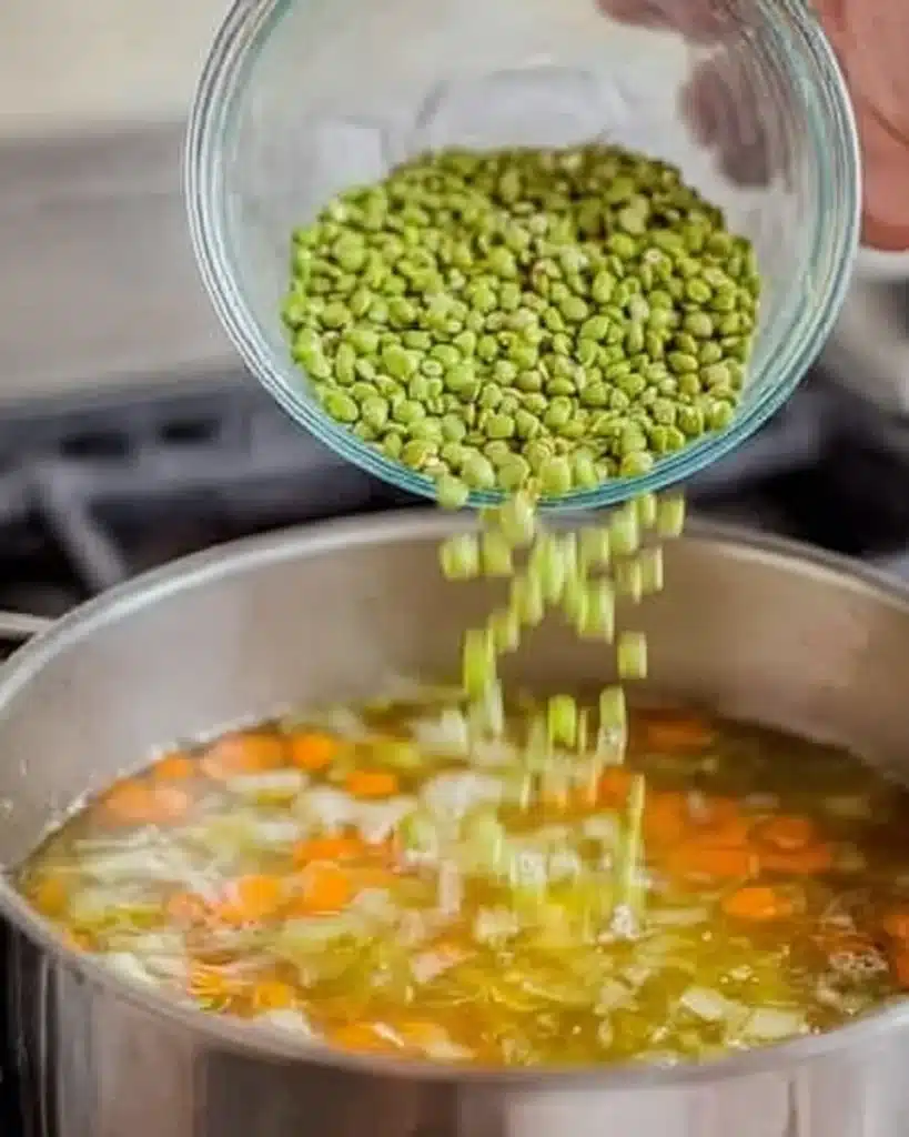 Split Pea Soup Recipe (Hearty and Flavorful Comfort Food) 4 Adding green split peas to simmering soup in a pot