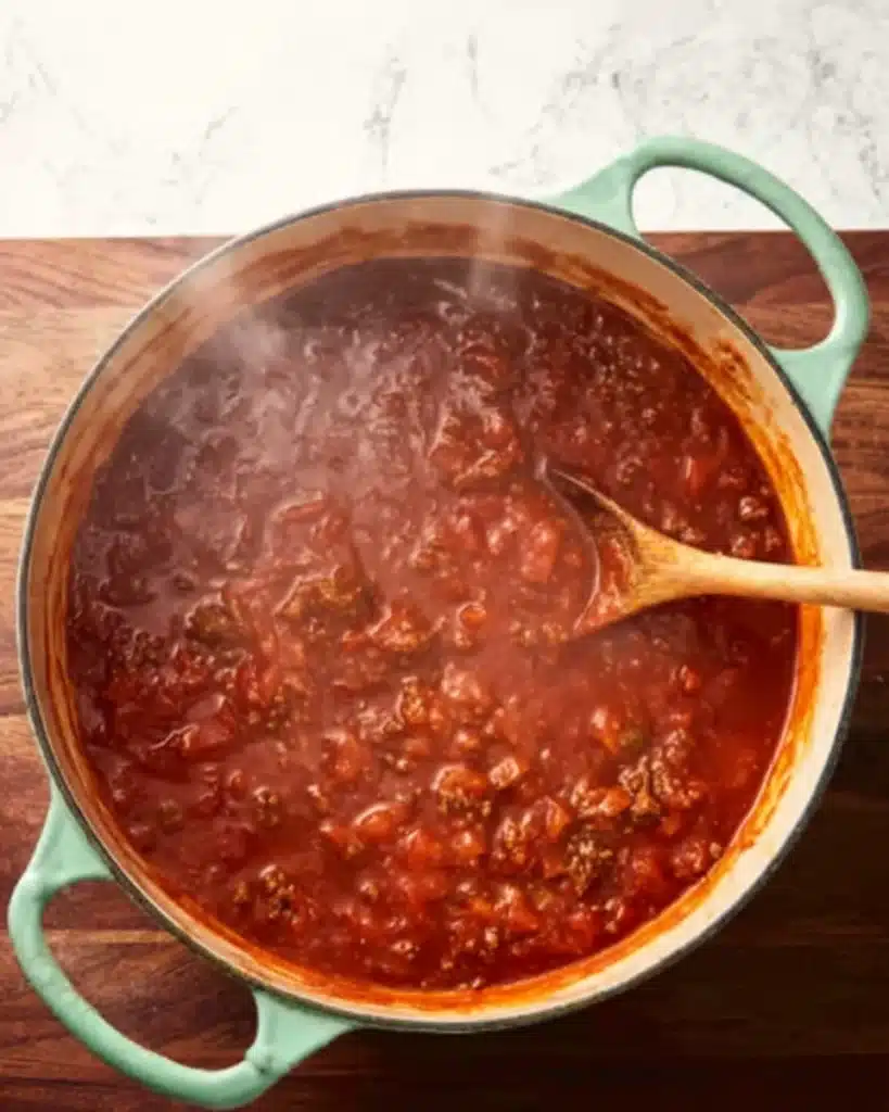 Creamy Tomato Beef Pasta (One Pot Dinner Recipe) 4 simmering tomato beef sauce in mint green pot with wooden spoon