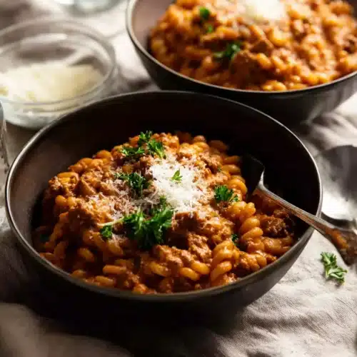 Creamy Tomato Beef Pasta (One Pot Dinner Recipe) 7 creamy tomato beef pasta in dark bowls topped with parmesan and parsley