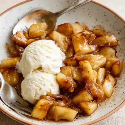 Warm air fryer apples with vanilla ice cream on a rustic plate