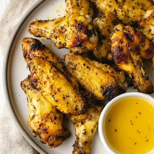 Crispy lemon pepper air fryer chicken wings with honey butter sauce on a plate