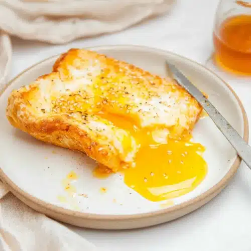 Air Fryer Egg And Cheese Toast 7 Air fryer egg and cheese toast with melted mozzarella and runny yolk on a white plate