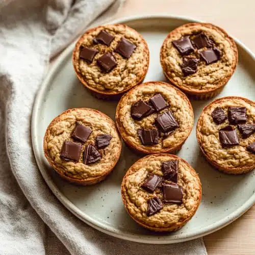 Banana oat muffins with dark chocolate chunks on a plate