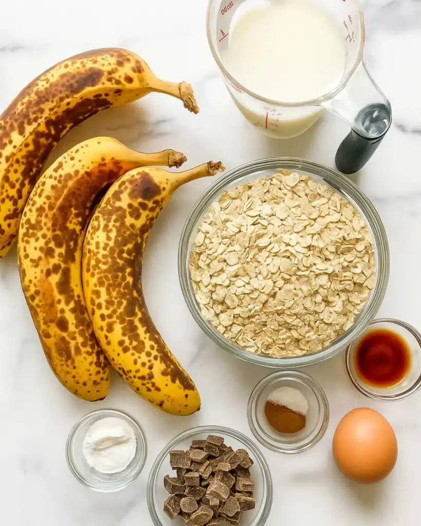 Banana oat muffin ingredients flat lay on white marble
