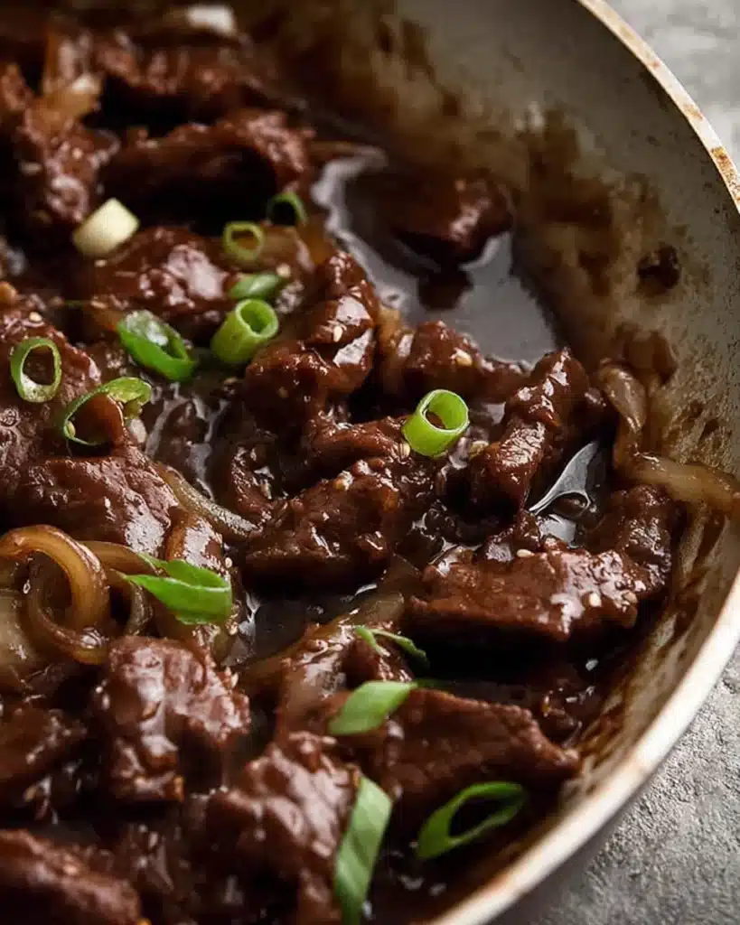 Close-up of beef stir fry with honey pepper sauce simmering in glossy brown glaze