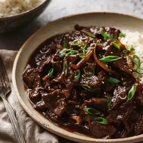 Beef stir fry with honey pepper sauce in a bowl topped with green onions