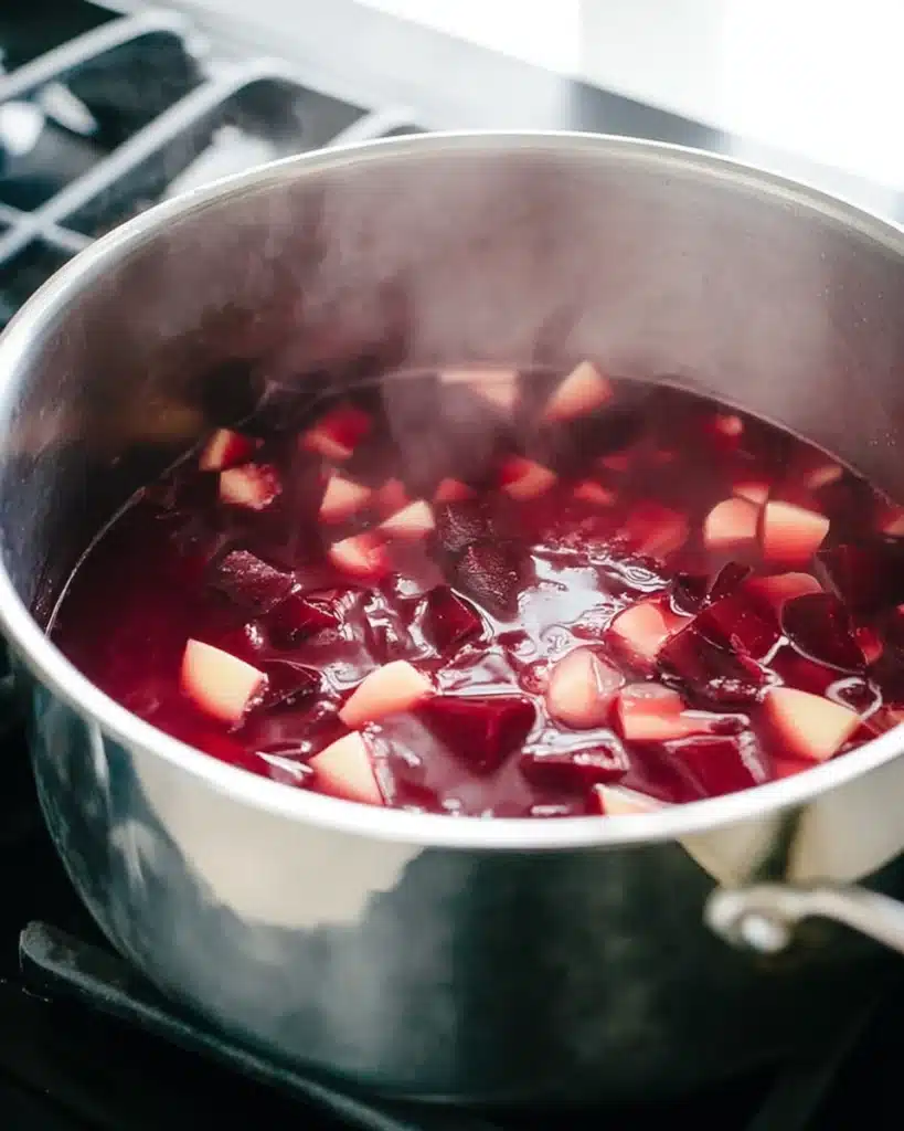 Beet and parsnip cubes simmering in a stainless-steel pot for beet soup