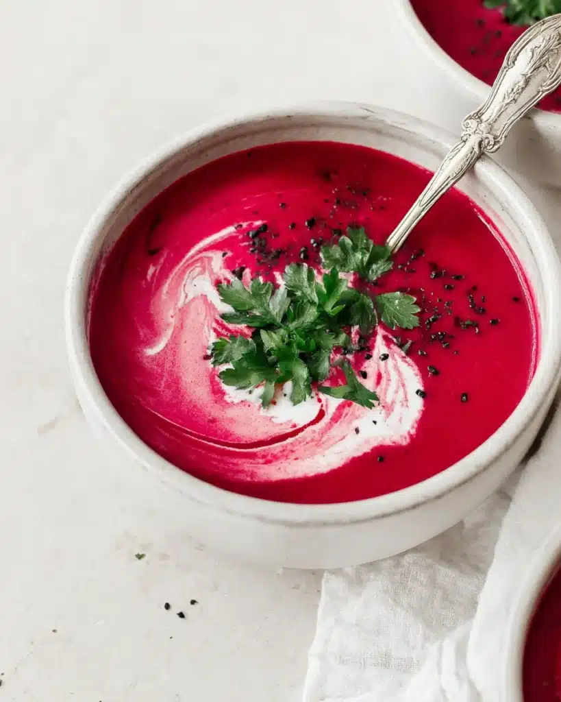 Creamy beet soup with coconut cream swirl and parsley garnish