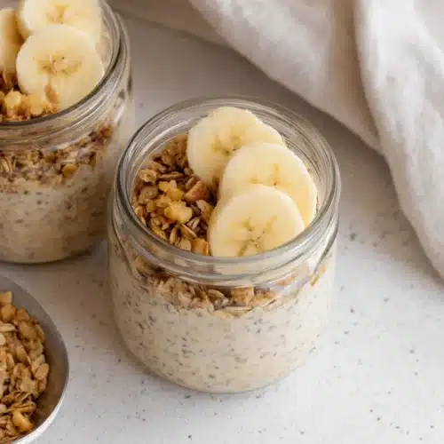 Brown sugar overnight oats in glass jars topped with banana slices and granola