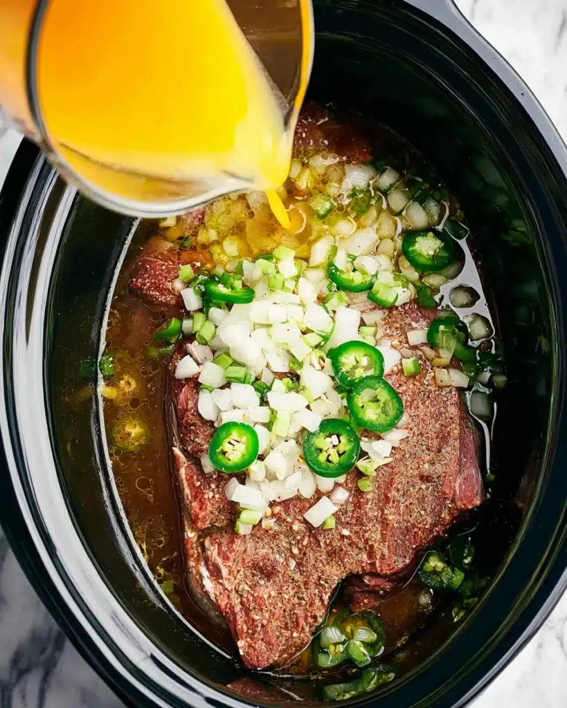 Slow Cooker Carnitas (Tender, Juicy, and Crispy Pork) 2 Seasoned pork with onions and jalapeños in slow cooker for carnitas