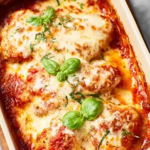 Cheesy Mozzarella Chicken Bake topped with melted cheese and marinara sauce in a baking dish