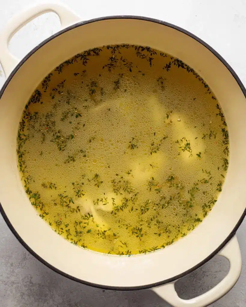 Chicken Bacon Rice Soup (Creamy, Hearty & Easy Recipe) 6 Chicken broth with herbs simmering in a Dutch oven for rice soup