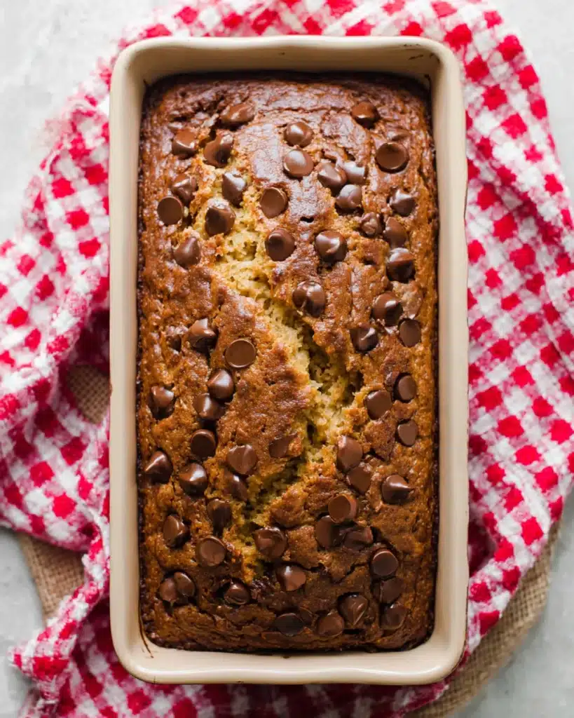 Freshly baked chocolate chip banana bread loaf in pan with melted chocolate chips