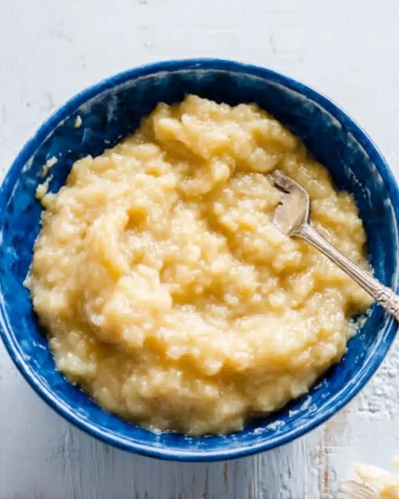 Mashed ripe bananas in a blue bowl with a fork for banana bread