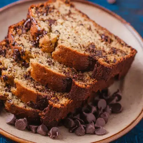 Moist chocolate chip banana bread slices on a blue plate with melted chocolate chips