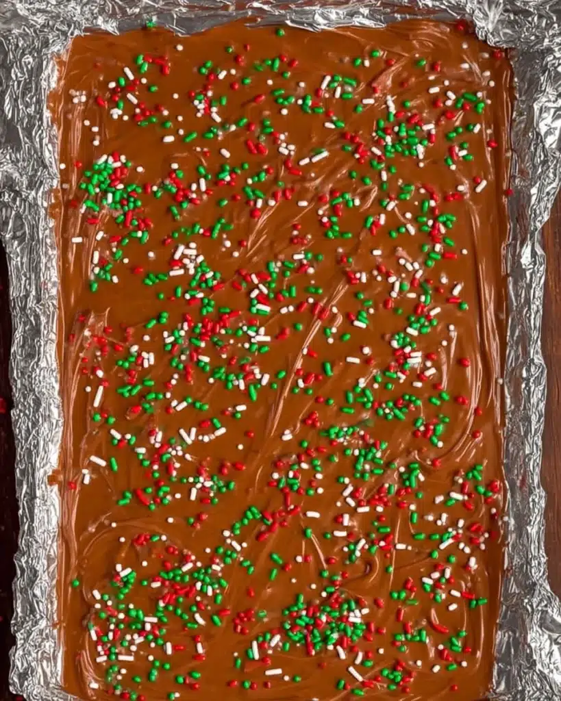 Melted chocolate topped with red, green, and white sprinkles for Christmas Crack