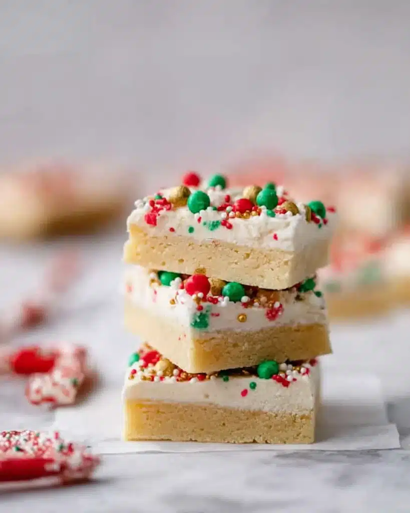 Christmas Sugar Cookie Bars (Soft, Chewy & Frosted) 6 Stack of frosted Christmas sugar cookie bars with sprinkles