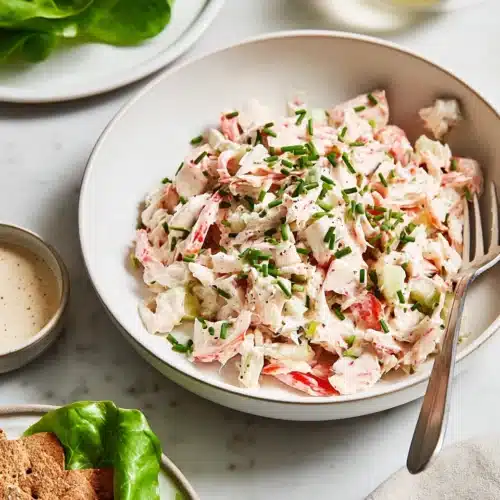 Creamy crab salad with celery, shallots, and chives in a white bowl
