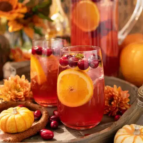 Cranberry orange prosecco punch with citrus slices and cranberries on a rustic fall table