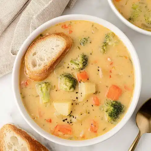 Creamy Vegetable Soup 7 Bowl of creamy vegetable soup with carrots, potatoes, broccoli, and crusty bread on marble surface