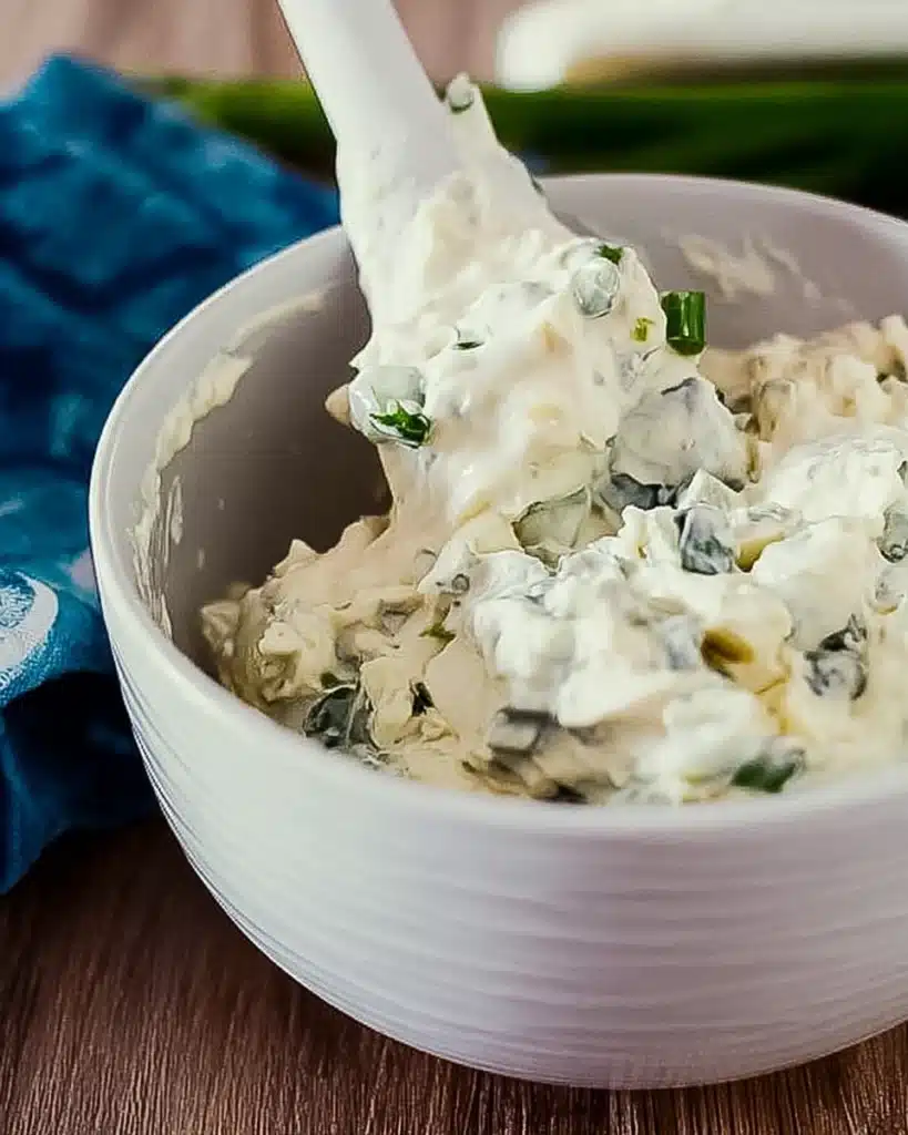 mixing creamy blue cheese dip with scallions in a white bowl