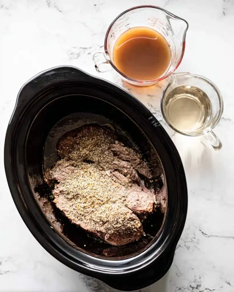 Beef chuck roast in slow cooker with onion soup mix and broth ingredients