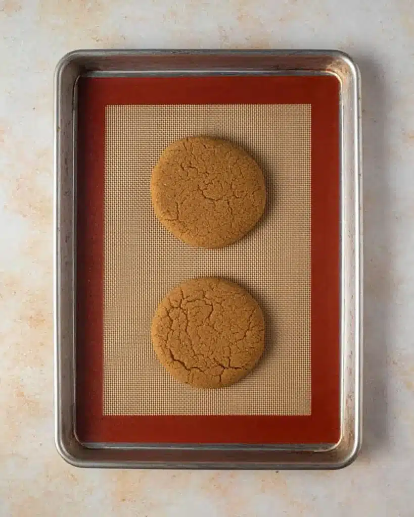 Soft Crumbl gingerbread cookie halves with frosting and gold star sprinkles on a cooling rack