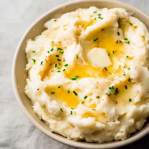 Easy Garlic Mashed Potatoes with melted butter and chives in a bowl