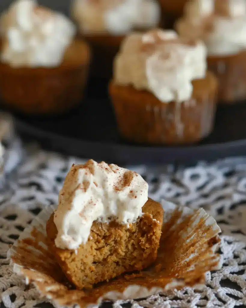 Pumpkin pie cupcake with a bite taken out topped with whipped cream