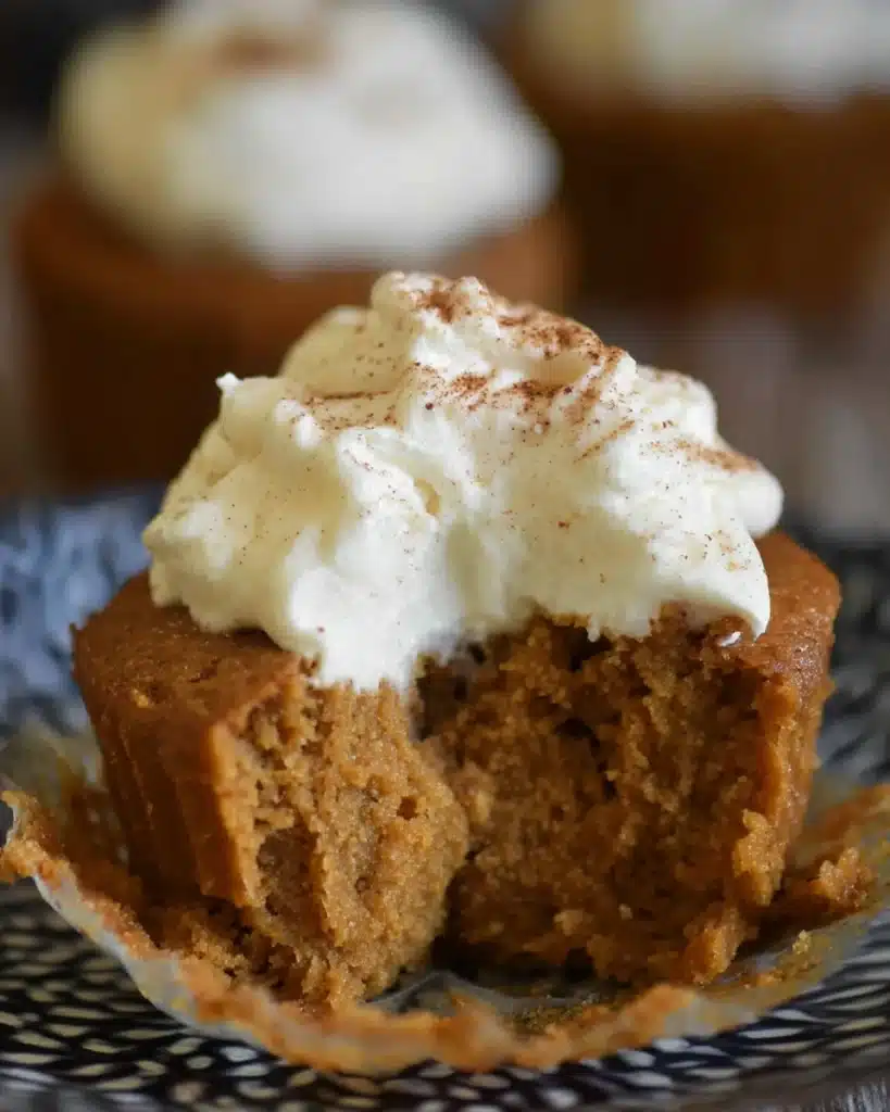 Half-eaten pumpkin pie cupcake with whipped cream and cinnamon