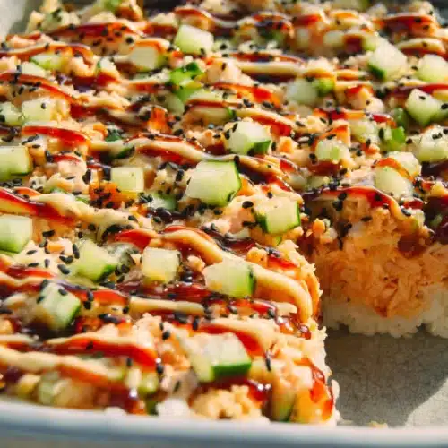 Easy sushi bake with creamy crab, cucumber, and spicy mayo drizzle in a white dish