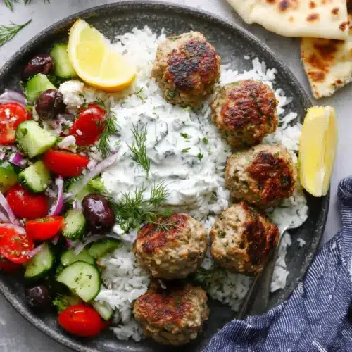 Greek turkey meatballs with tzatziki, rice, and fresh Greek salad on a plate