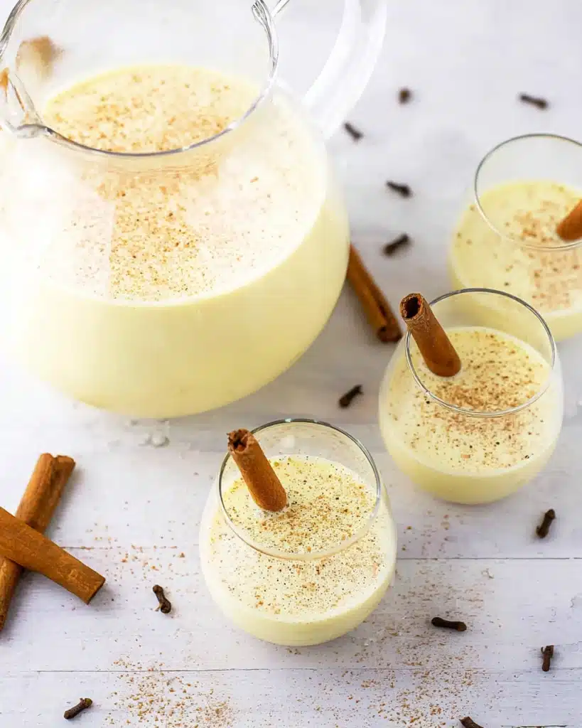 Homemade Eggnog Recipe 3 Homemade eggnog in pitcher and glasses topped with cinnamon and nutmeg