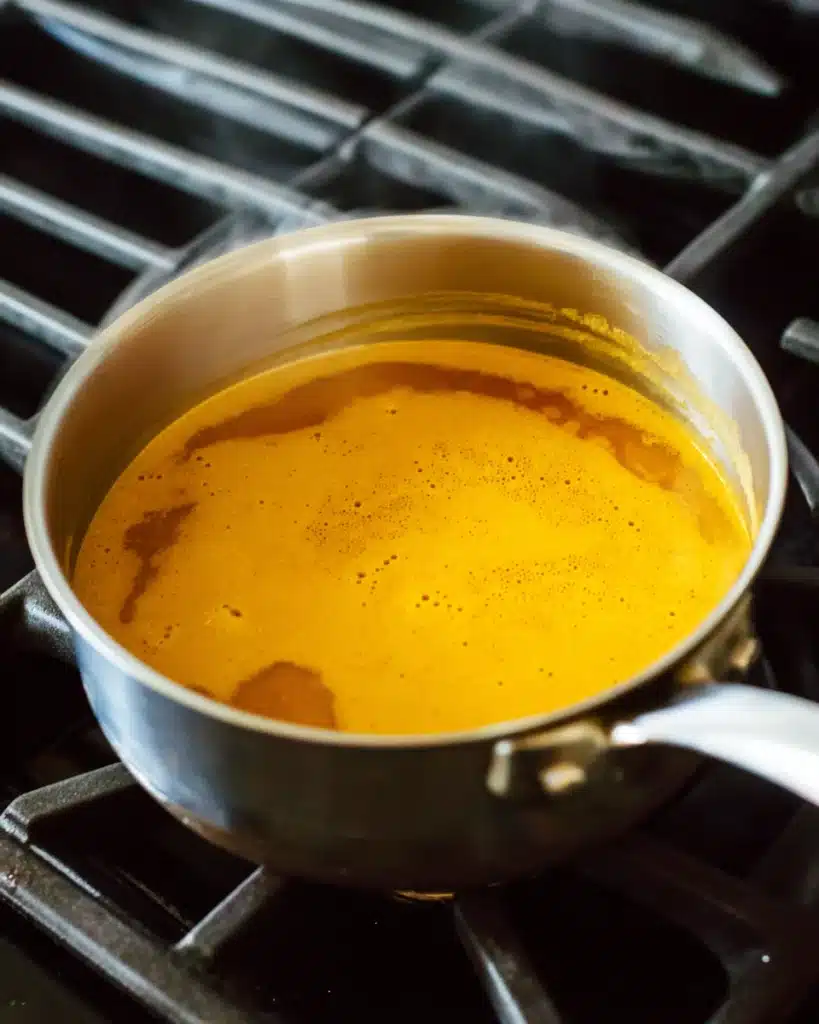 Golden Jamu Juice simmering in a saucepan on the stove