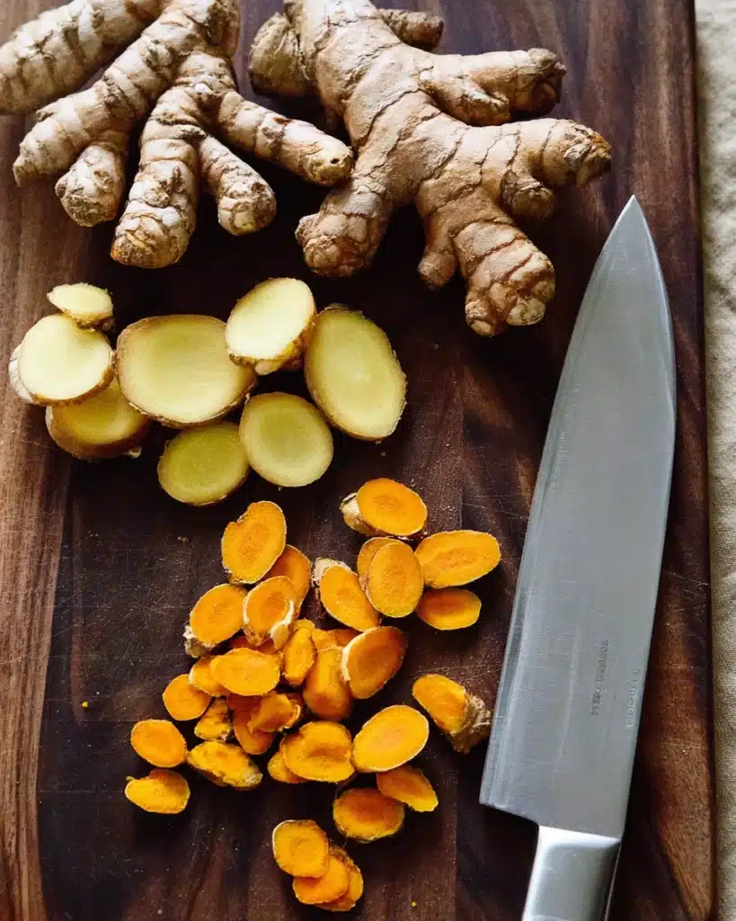 Fresh turmeric and ginger roots sliced on a wooden board for Jamu Juice recipe