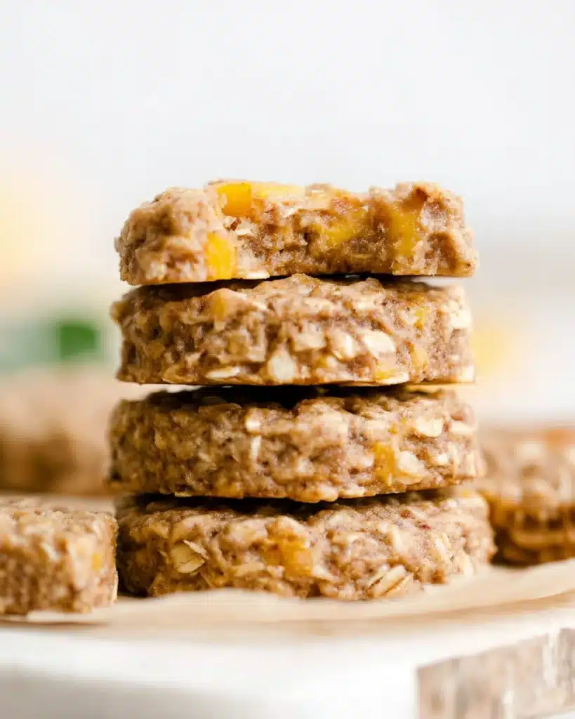 Stack of chewy peach oatmeal breakfast cookies with visible peach chunks on parchment paper