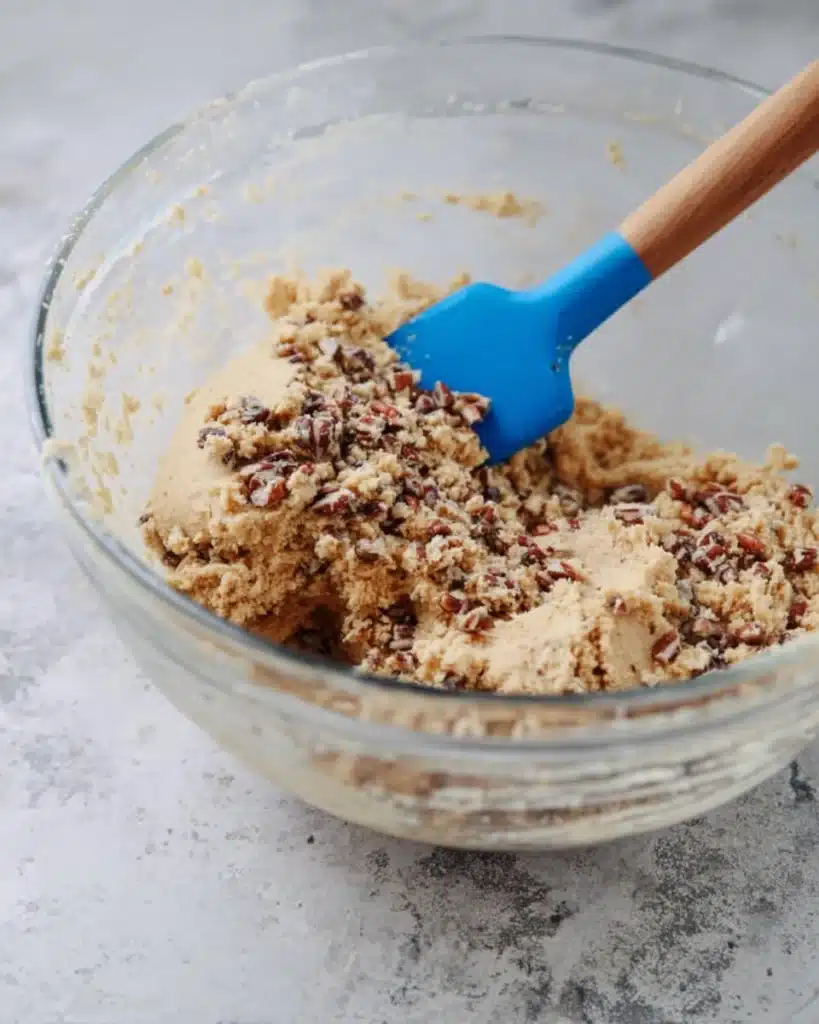 Russian Tea Cakes dough mixed with chopped nuts in a glass bowl