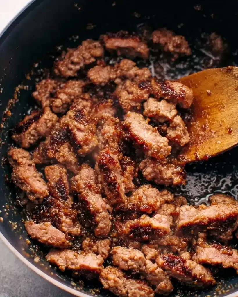 Sausage Pasta Soup (Creamy and Hearty One-Pot Meal) 2 Browned Italian sausage in pot with wooden spoon