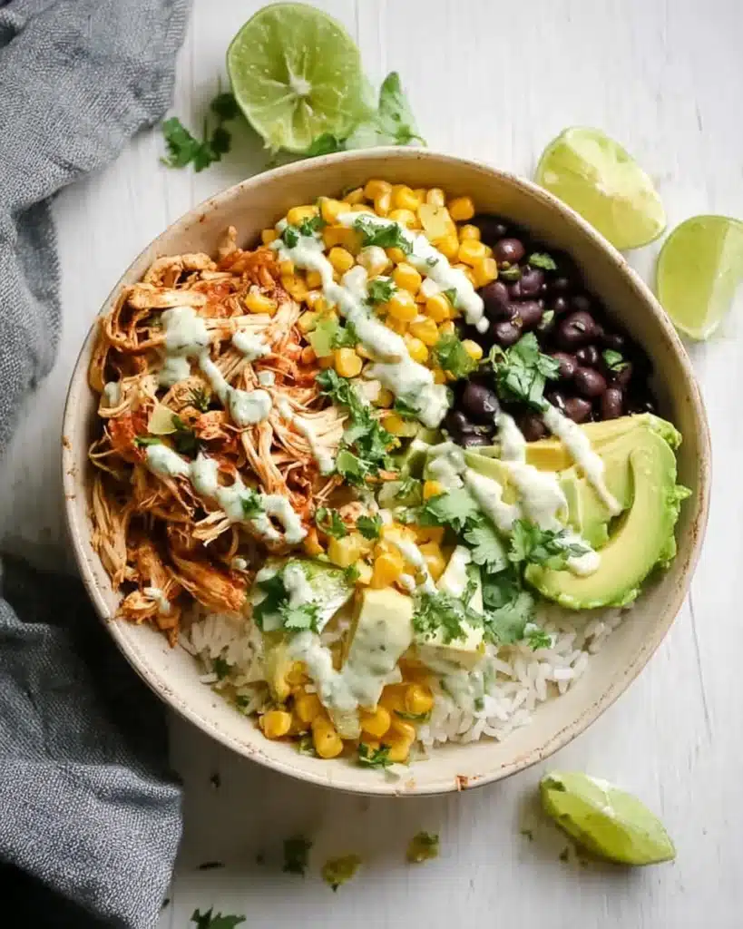 Slow cooker chicken burrito bowl with shredded chicken, rice, beans, corn, and avocado
