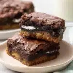 Stacked Slutty Brownies with cookie dough, Oreo layer, and fudgy brownie on a plate