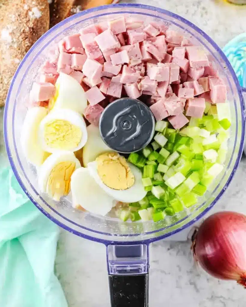 Diced ham, celery, and eggs in a food processor for ham salad