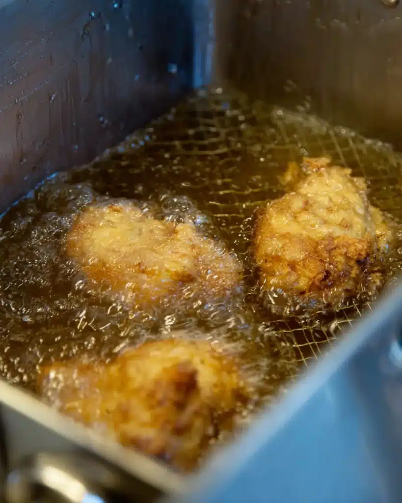 Chicken frying in hot oil inside a deep fryer for Southern fried chicken