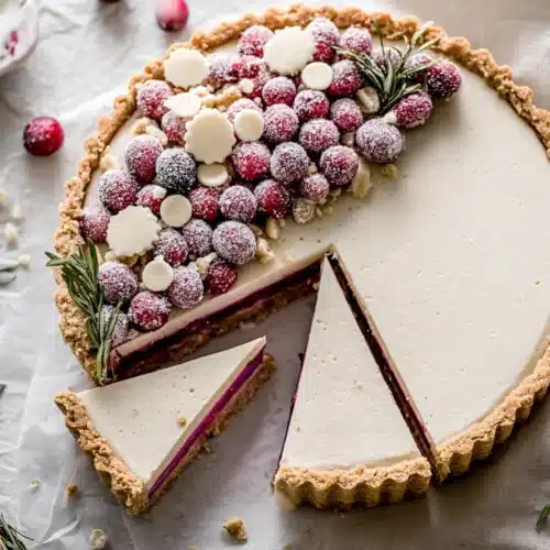 White Chocolate Cranberry Tart with sugared cranberries and rosemary on light background