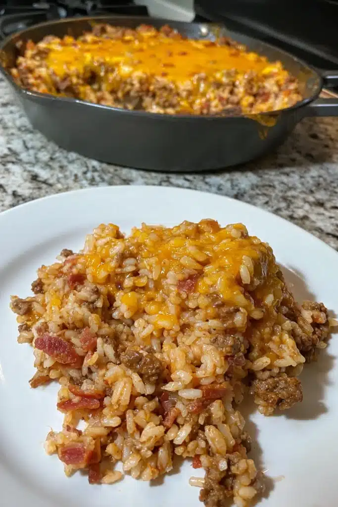 Plated bacon cheeseburger rice skillet with melted cheddar and bacon on white dish