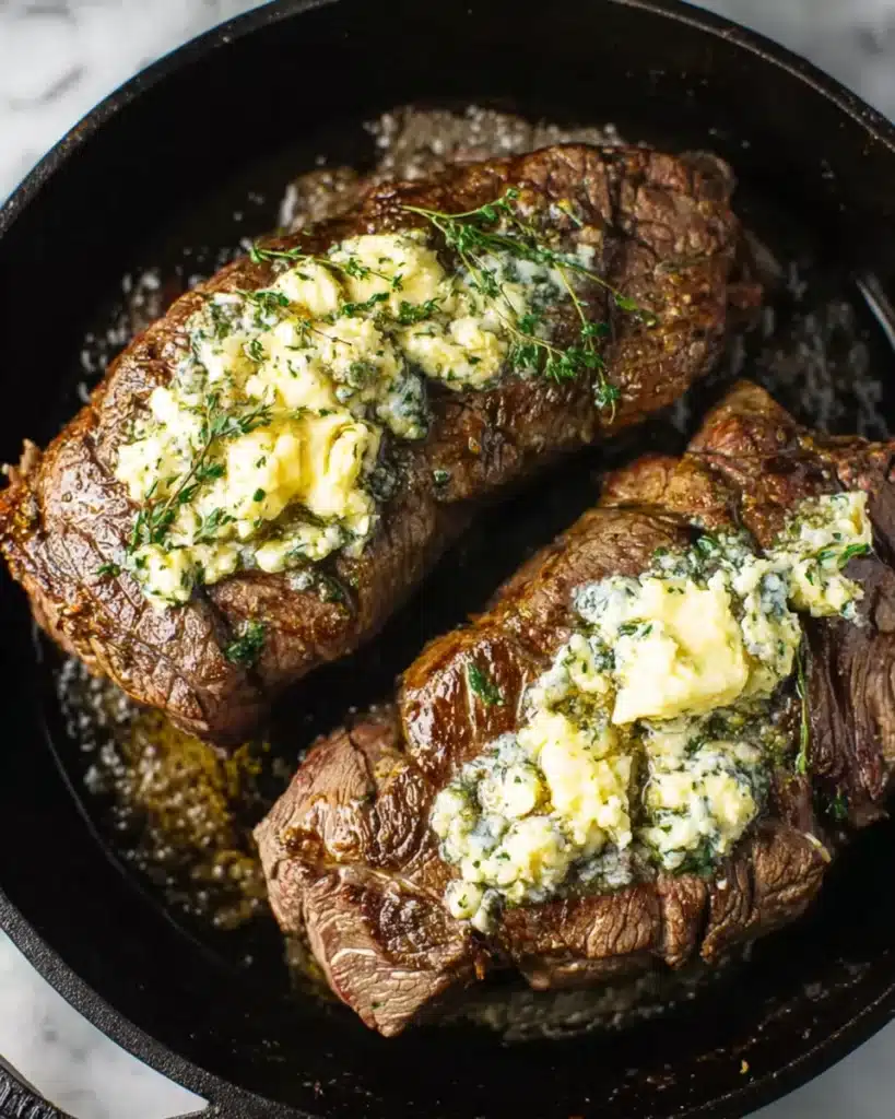 Beef tenderloin roast topped with melting garlic herb butter in cast iron skillet