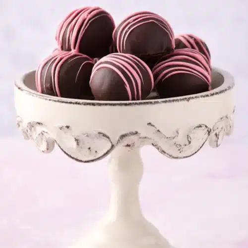 Chocolate raspberry truffles with pink drizzle on white dessert stand