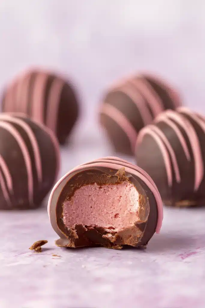 Bitten chocolate raspberry truffle showing pink creamy filling